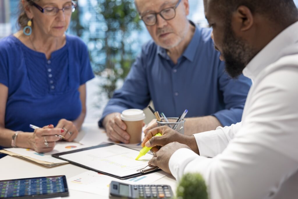 Three professionals reviewing documents together at a table.
