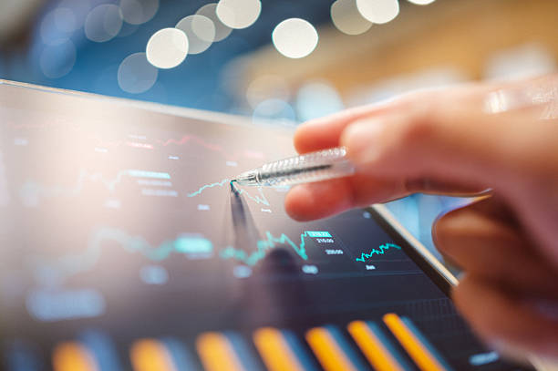 Hand pointing to a rising line chart on a tablet.
