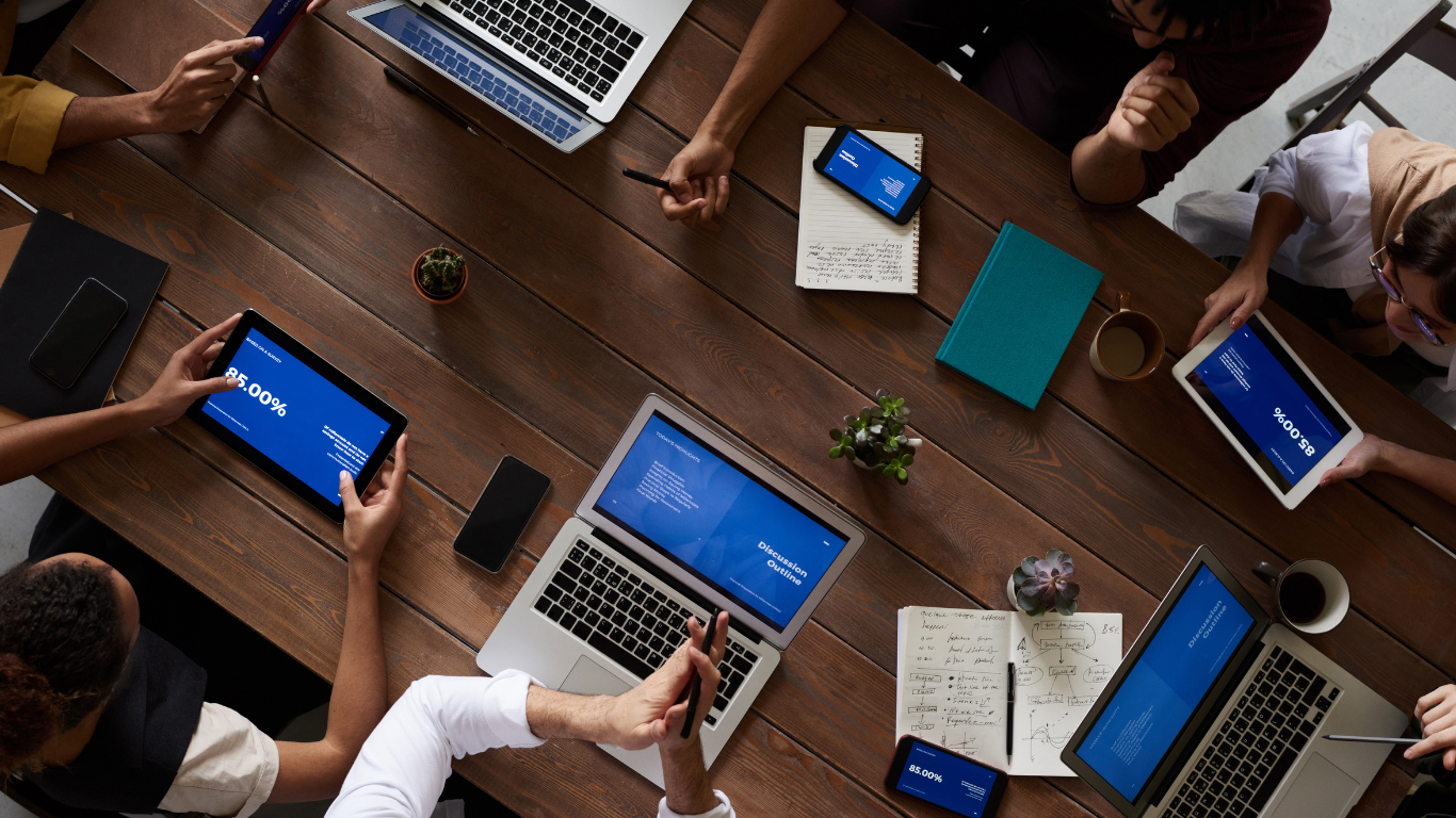 Financial advisers collaborating around a table with laptops and tablets.
