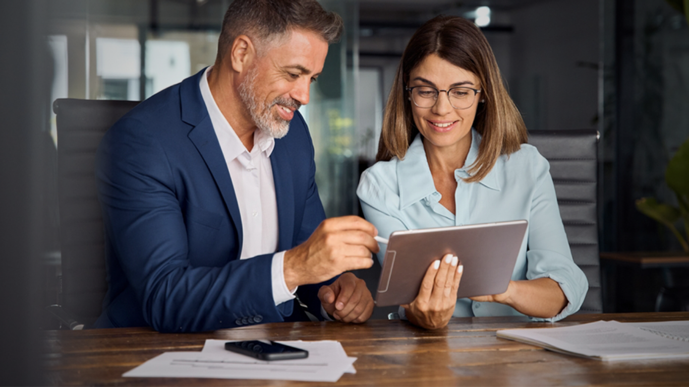 A financial adviser consulting with a client using a digital tablet.